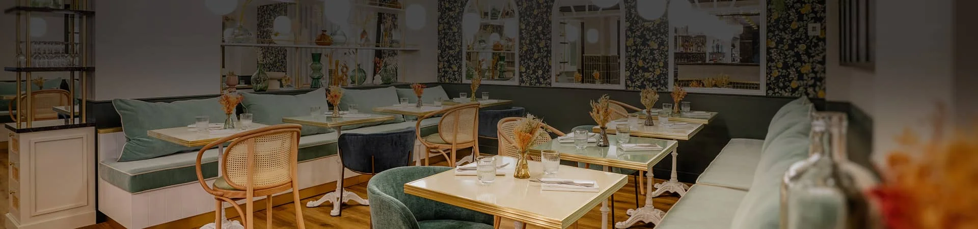 Salle du restaurant Bistrot Yonnais à La Roche-sur-Yon pour les repas de groupe des fêtes, avec banquettes vert d'eau, papier peint floral et miroirs en arche