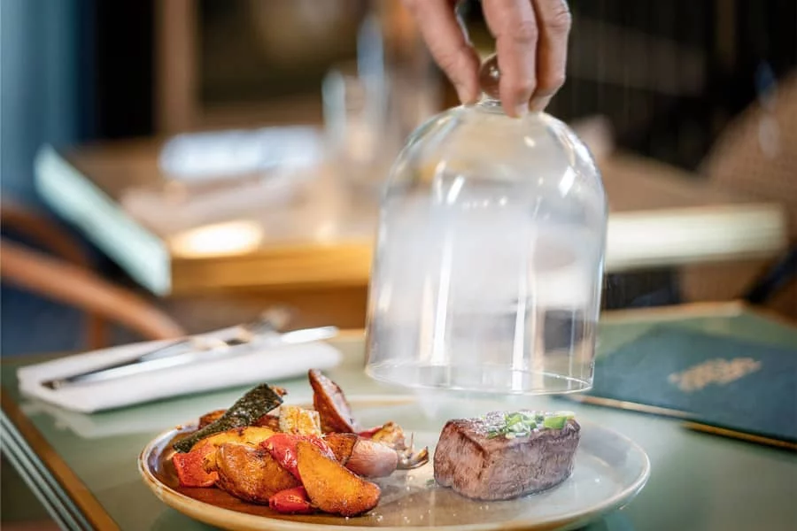 Plat signature du Bistro Yonnais à La Roche-sur-Yon, filet de boeuf sous cloche avec accompagnement de saison et présentation raffinée.